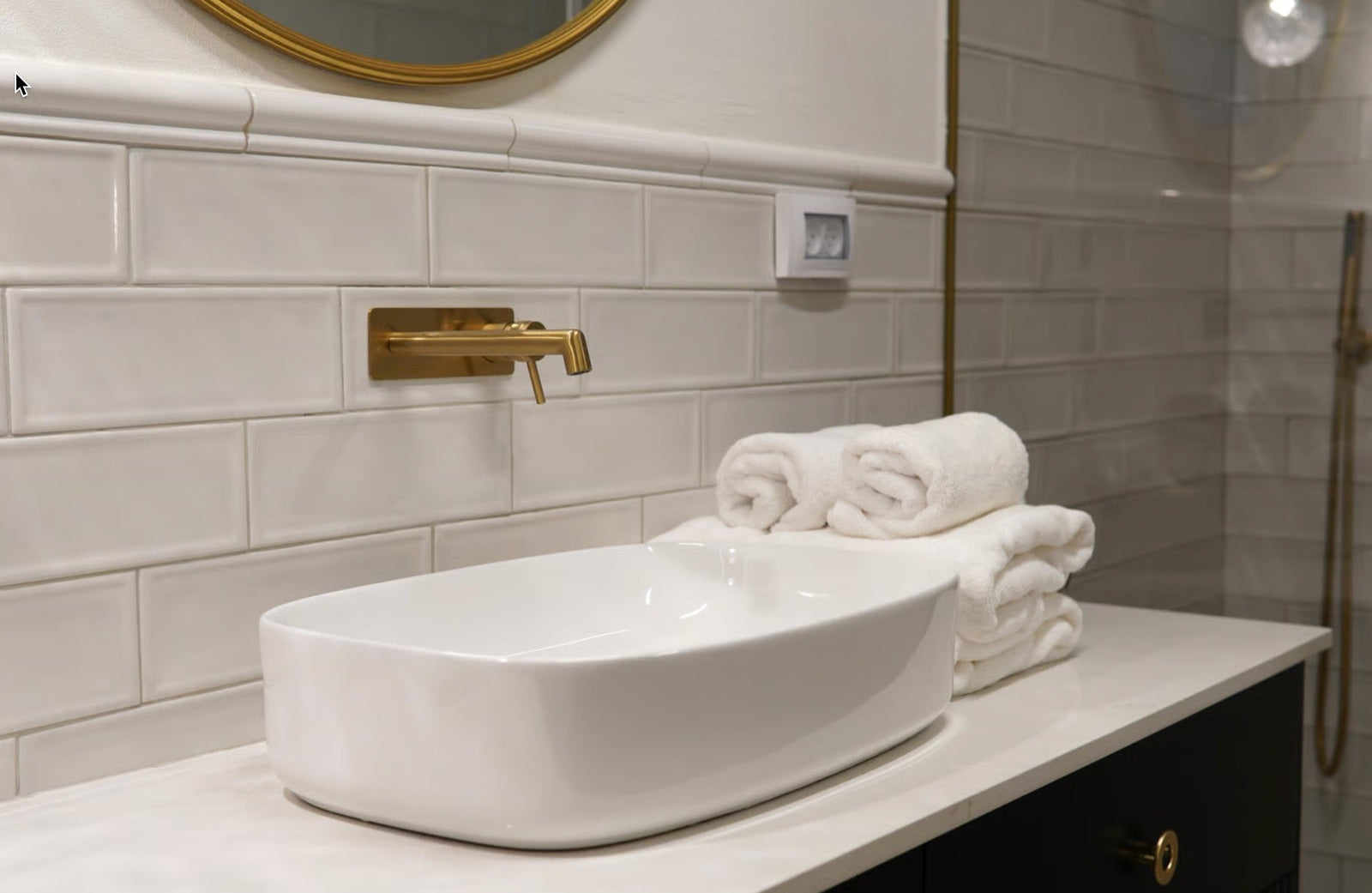 A luxury bathroom lifestyle shot featuring neatly stacked Egyptian cotton towels resting beside a polished stone countertop and brushed brass bathroom fittings.