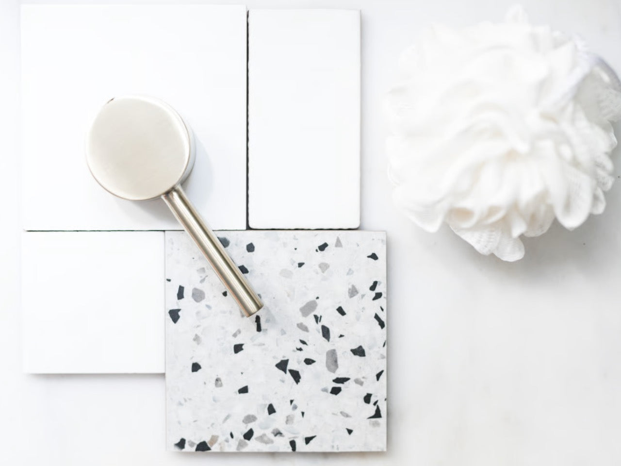 A luxurious hospitality mood board presentation displaying pristine, wash cloth resting beside samples of brushed golden hardware and polished Terrazzo tile.