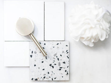 A luxurious hospitality mood board presentation displaying pristine, wash cloth resting beside samples of brushed golden hardware and polished Terrazzo tile.