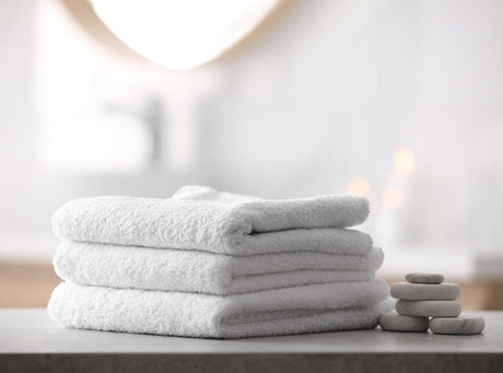 •	A beautifully presented luxury wellness resort bathroom, with crisply folded plush white Egyptian cotton towels neatly resting on a textured slate vanity unit.